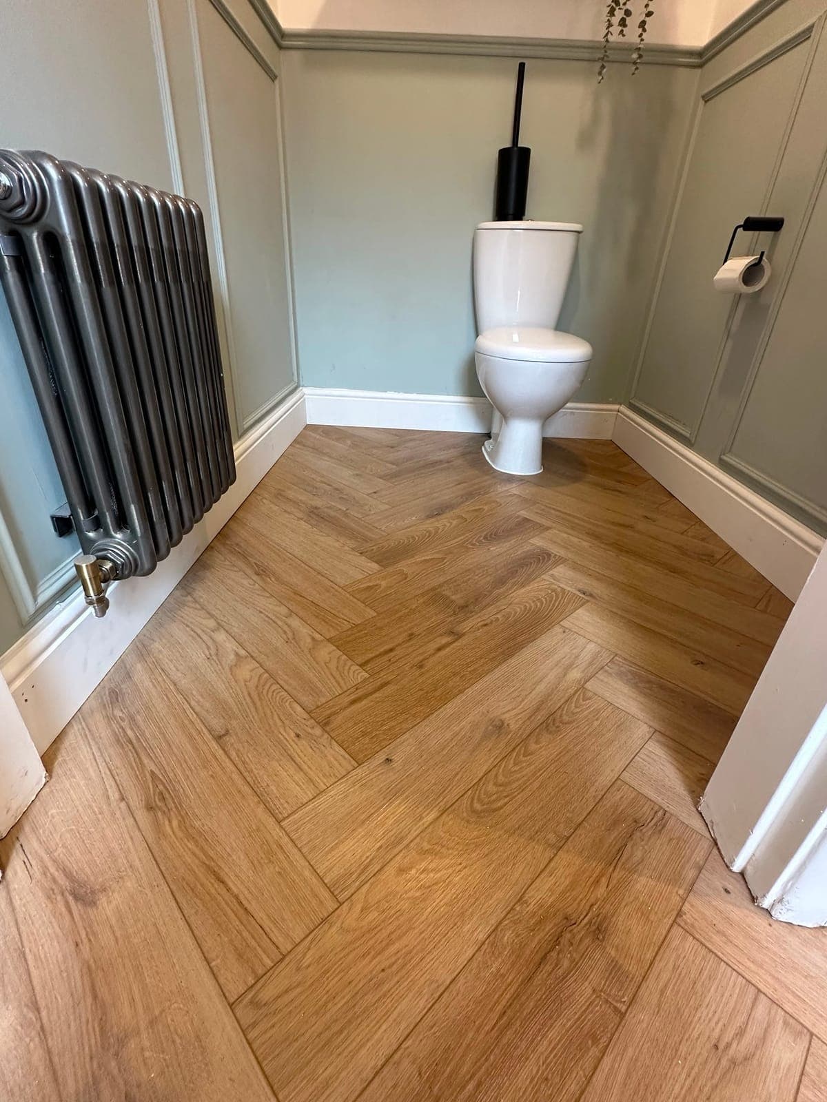 Cloakroom Flooring — Oak herringbone flooring fitted around wall panelling and a column radiator.