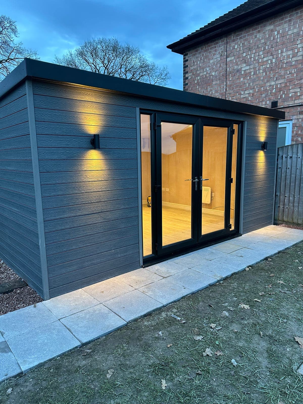 Garden Room Build — Composite-clad garden room with French doors and exterior wall lighting.
