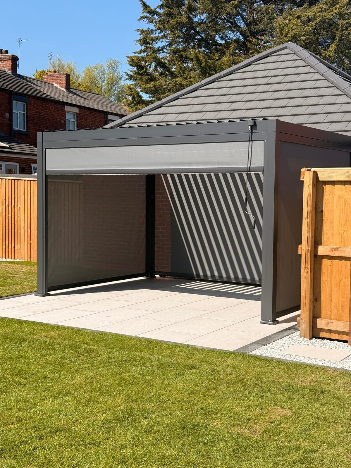 Louvered Pergola — Aluminium louvered pergola with retractable privacy screens on a porcelain patio.