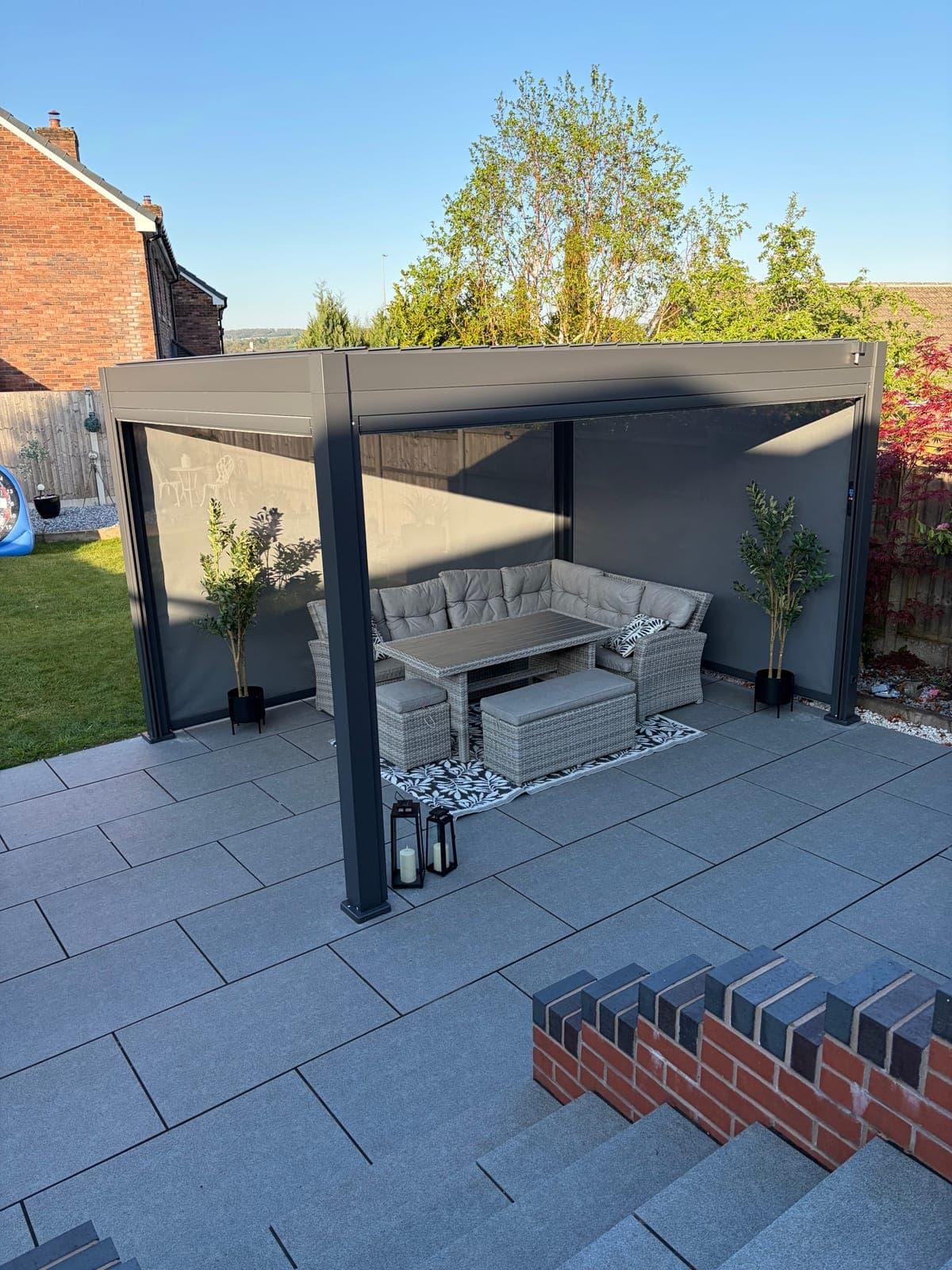 Pergola Seating Area — Pergola sheltering a rattan corner sofa on a porcelain patio.