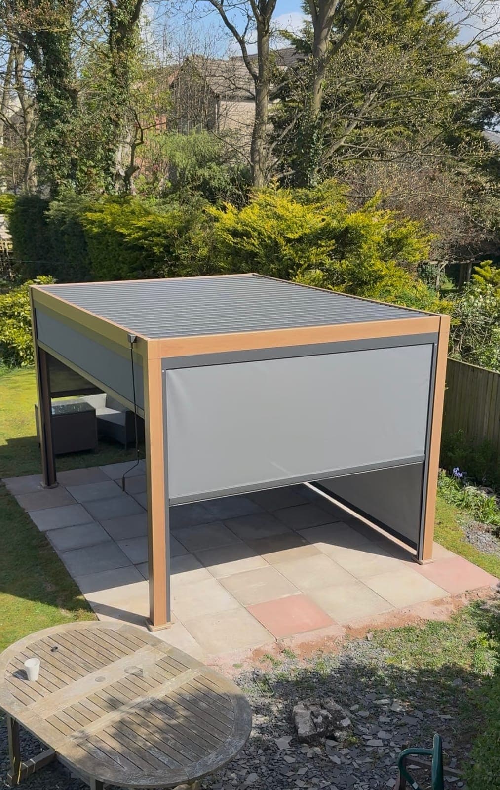 Pergola with Privacy Blinds — Louvered pergola with integrated side blinds on a sandstone patio.