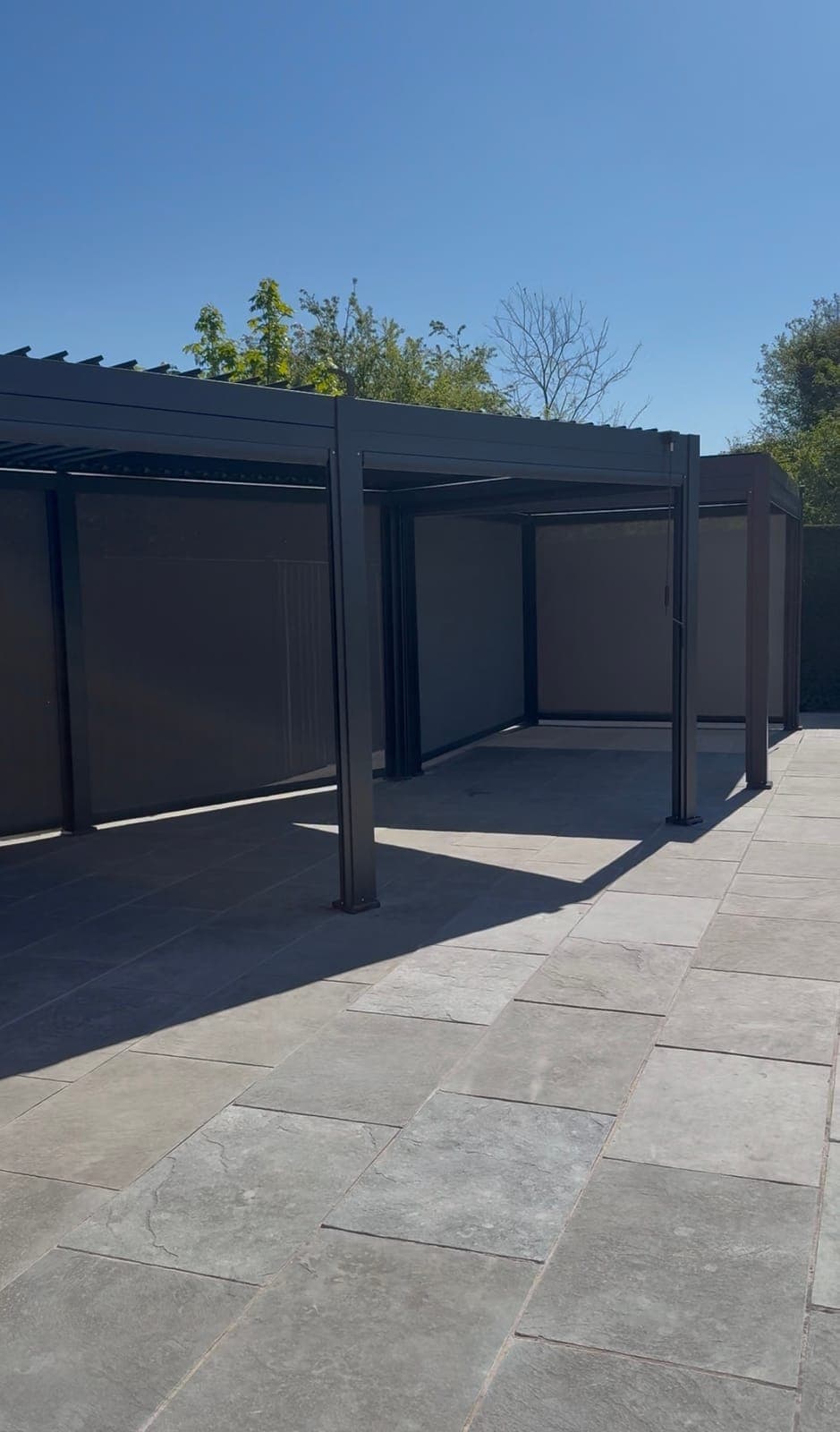 Pergola with Side Screens — Aluminium louvered pergola with integrated side screens over a paved patio.